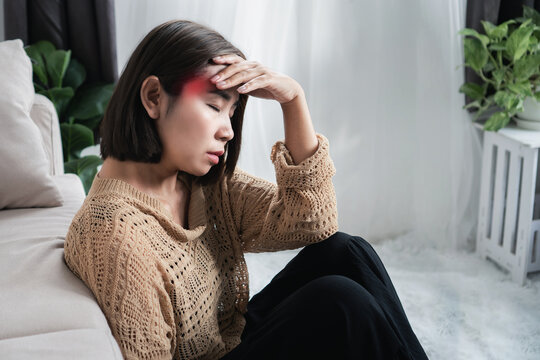 asian woman holding her right temple in pain, experiencing tension or migraine headache from anxiety, dehydration, or poor posture