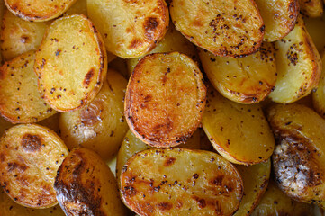 Baked potato halves with a crispy golden crust, seasoned with spices and drizzled with oil. Perfectly roasted potatoes, delicious comfort food, rustic cooking, side dish.