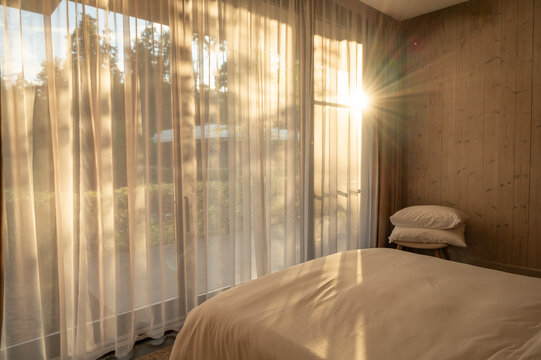 Sunlight illuminating bedroom through sheer curtains in the early morning