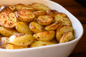 Baked potato halves with a crispy golden crust, seasoned with spices and drizzled with oil. Perfectly roasted potatoes, delicious comfort food, rustic cooking, side dish.