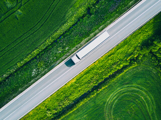 Aerial view of a road with a logistics truck driving on it in green summer weather in Finland, drone photo.