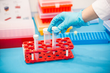 Scientist handling a test tube in a laboratory with colorful equipment in the background