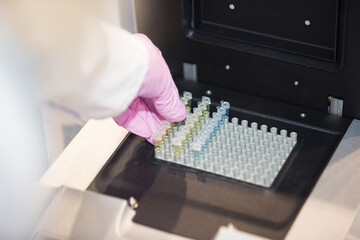 Scientist handling a test tube in a laboratory with colorful equipment in the background