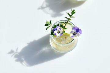 Iced lemonade with edible pansy flowers, lime and mayran. Refreshing summer drink. Healthy organic...