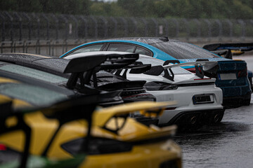 Rain-soaked sports cars lined up on a wet track