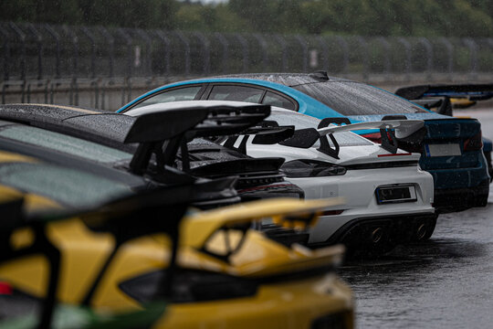 Rain-soaked sports cars lined up on a wet track