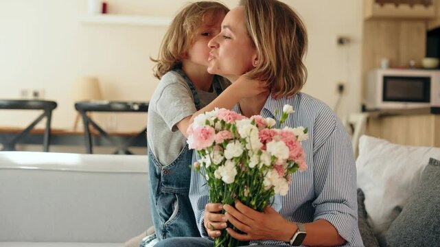 Young boy gives his mother a bouquet of flowers at home in a warm and cozy setting. She smiles with joy and gratitude. Concept of Mother's Day celebration and family love. Mid-range shot natural light - Powered by Adobe