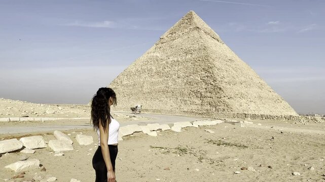 Witness a tourist walking through the desert at the Great Pyramid of Giza, Egypt, one of the ancient world's wonders. Explore Keops's legacy on this historic plateau.