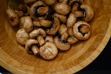 Marinated champignon mushrooms in a wooden bowl, ready for grilling. Fresh, rustic ingredients for outdoor BBQ. Natural light, healthy plant-based cooking scene.
