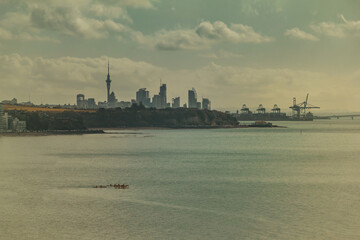 A scenic coastal view of Auckland, New Zealand, featuring the city skyline with the Sky Tower in...