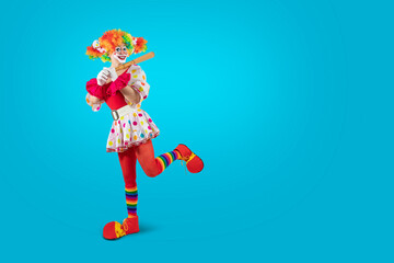 Funny female clown club-swinging. Entertainer woman Joker in colorful suit and wig. Buffoon with...