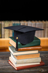 Stacks of books, Square academic cap or graduation hat against library shelves with books. Concept...
