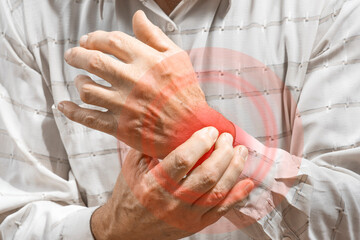 Arthritis symptoms, suffering from pain. The hands of the senior man massage wrist. Inflamed male...