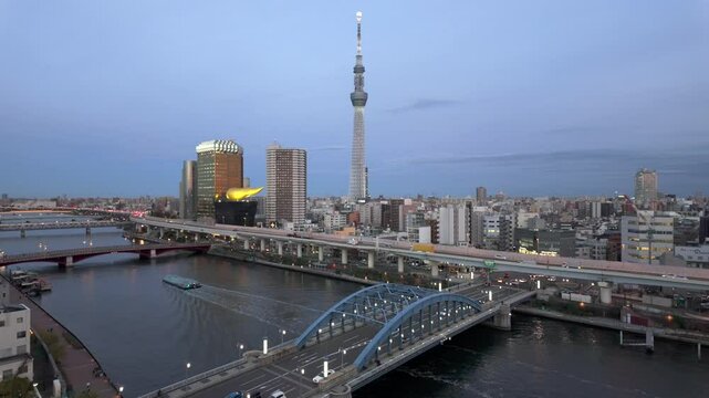 Panning shot of Tokyo skyline and Sumida River at dusk in Sumida City, central Tokyo, Japan.
