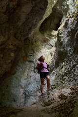Woman hiker standing inside a narrow rocky canyon looking up.........