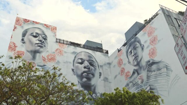 Close up shot of a mural at Wynwood Art District, Miami, depicting African and Latin children holding roses, with one extending hands in a prayer-like gesture.