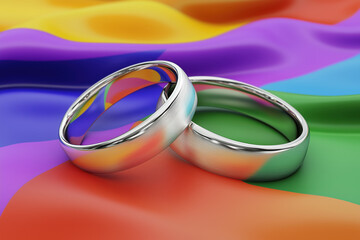 Closeup of wedding rings positioned on a vibrant rainbow LGBT flag representing love and inclusivity