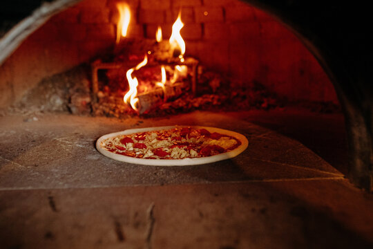 Wood-Fired Oven with Pizza Cooking Over Flames in Rustic Kitchen