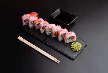Colorful sushi rolls with wasabi and soy sauce on a sleek slate plate