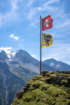 Swiss flag an flag of canton uri waving in the wind at a mountain hut in Switzerland