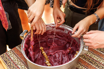 A group of people are gathered around a large pot, working together to create Authentic Georgian Churchkhela