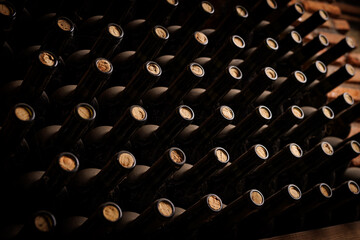 A row of wine bottles with corks in them. The corks are brown and the bottles are black