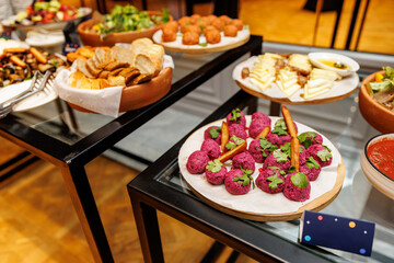 A table with a variety of food items including a plate of meatballs and a bowl of fruit