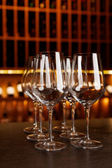 A row of wine glasses are lined up on a counter. The glasses are all clear and appear to be empty