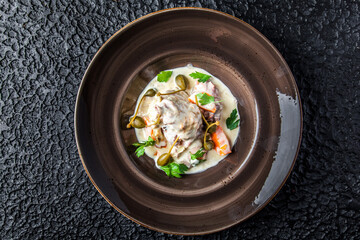 Creamy Capers Dish in black plate on black background.