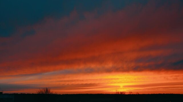 Evening sky at sunset background. Dark clouds hanging above horizon. Majestic cloudscape in blue, orange shades. Grey cloudlets bringing rain. Countryside skyline in twilight time