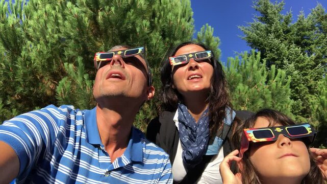 Excited Caucasian family watching the total solar eclipse together with protective glasses