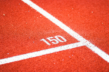 Distance lane markings on a red running track at an athletics stadium. White numbers and lines on...