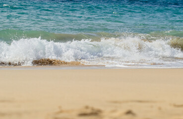 Atlantic Ocean waves crash on a sandy beach in Lanzarote. The blue sea and soft sand attract tourists to this secluded, sunny beach.