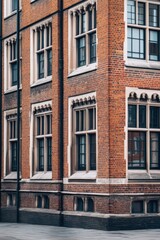 Fototapeta premium Historical brick building with intricate window designs showcases architectural beauty in a city setting during daylight hours