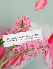 Hyazinthe vor mint-pinker Malerei mit Achtsamkeitsspruch auf Zettel