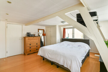 This serene bedroom features a comfortable bed, wooden furniture, and ample natural light, creating...