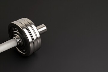 Shiny dumbbell rests on dark surface, showcasing strength and fi
