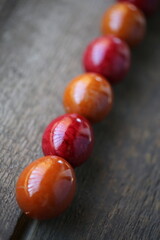 Easter red and orange eggs are lying on the wooden table. The eggs are arranged diagonally. The light is beautifully reflected in the eggs through the balcony railing.