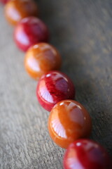 Easter red and orange eggs are lying on the wooden table. The eggs are arranged diagonally. The light is beautifully reflected in the eggs through the balcony railing.