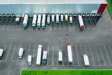 Aerial view of different logistic trucks at the loading docks of a large distribution warehouse