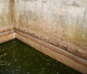 Abstract angle of an old, deep farm water well with stagnant green water.