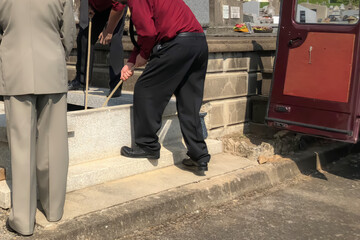 Porters lower the coffin into the grave