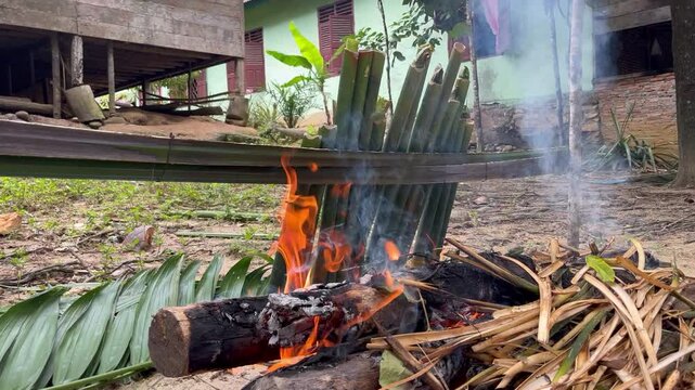 The process of making lemang, a food made from sticky rice which is put into bamboo lined with banana leaves.