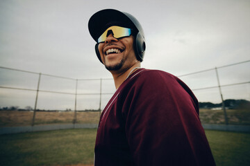 Smiling baseball player wearing polarized sunglasses on field, exuding a professional and confident demeanor