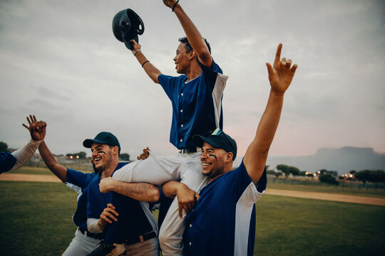 Baseball team celebrating victory with captain raised on shoulders of teammates