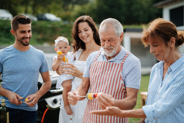 Three generations of family preparing food for a spring weekend barbecue.