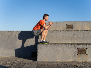 Sportsman performing squats on concrete steps at the breakwater