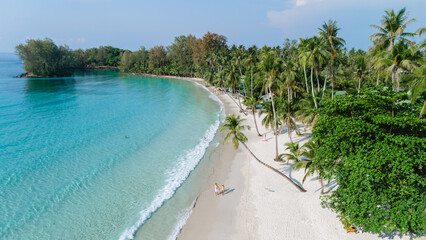 Pristine white sand stretches along the shoreline of Koh Kood Island, Thailand, as calm turquoise waters gently lap at the beach.