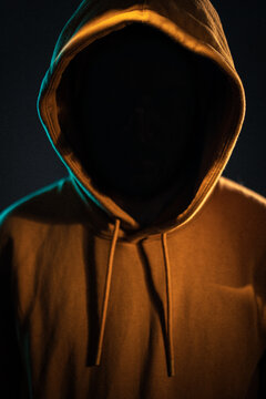 un homme avec le visage dans l'ombre et la capuche d'un sweat sur la t&ecirc;te