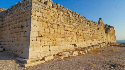Fototapeta premium A massive stone wall with a bright blue sky in the background, perfect for landscape or architecture photography